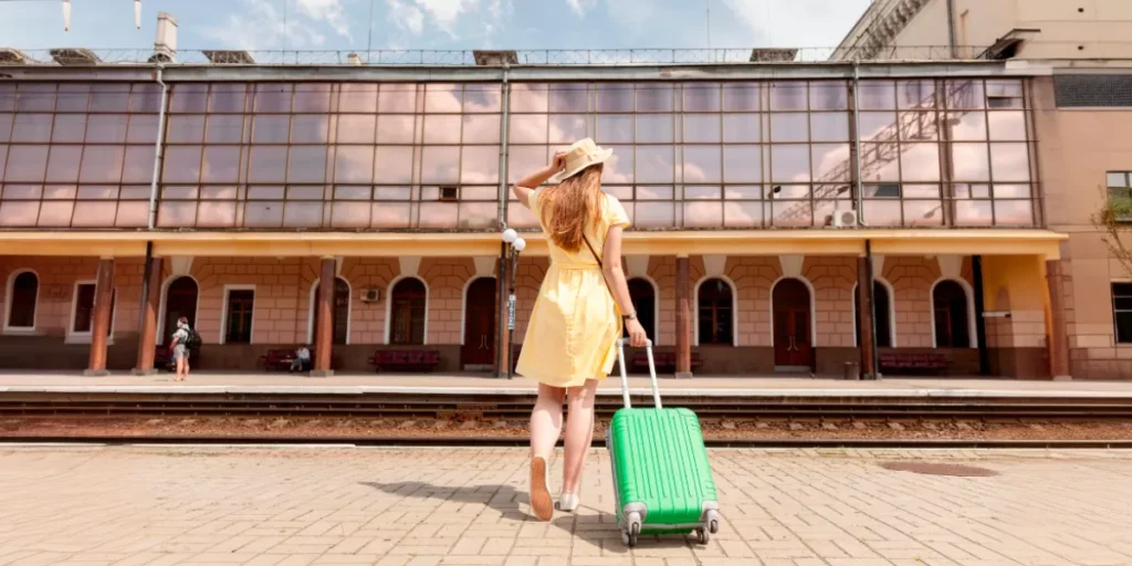 Mujer-con-vestido-amarillo-y-maleta-verde-en-una-estacion-de-tren